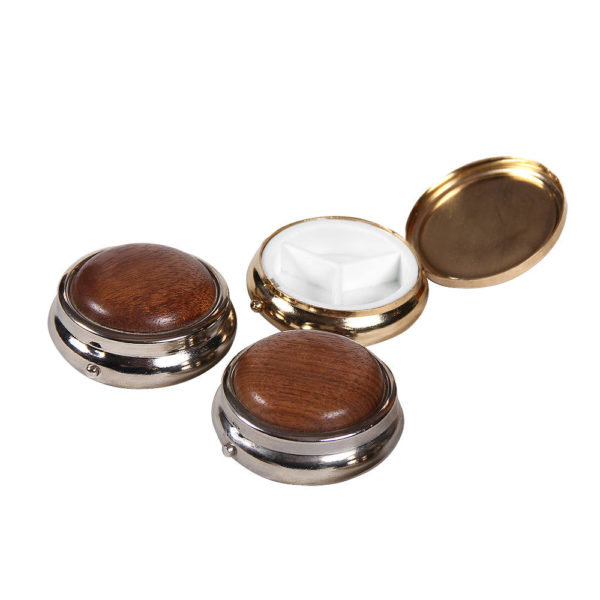 A collection of small round wooden pill boxes, showing the outside and inside of the pill box.